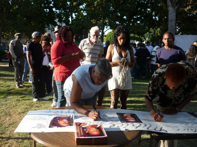 Dozens of Mitrice Richardson supporters stand in line Monday night at Leimert Park to sign a poster in her memory.