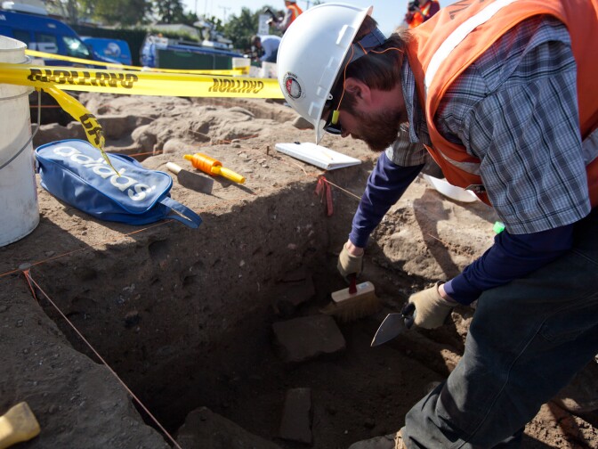 Archaeologist Ryan Glenn clears dirt at a dig site near San Gabriel Mission. The dig has unearthed items dating back to the 18th century.