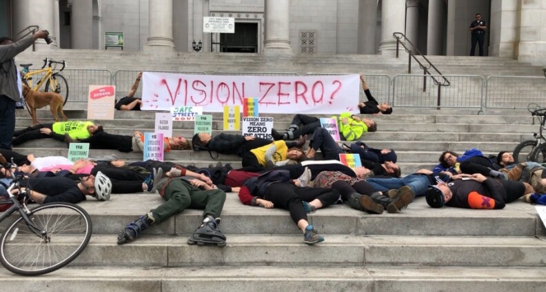 More then a dozen people lie down on the front steps of L.A. City Hall in front of a banner that reads Vision Zero?