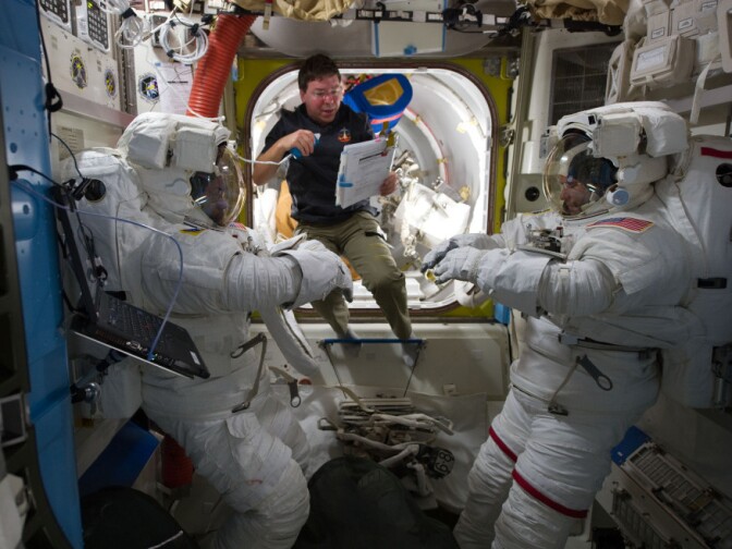 Mission Specialist Michael Barratt prepares his fellow astronauts for a spacewalk in the airlock of the International Space Station in February 2011.