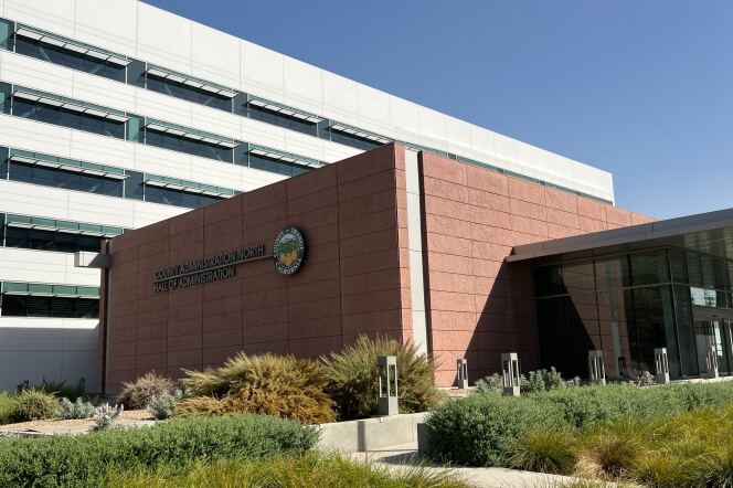 The exterior of a building has a terra cotta-colored stone wall with the words : County of Orange County Administration North 