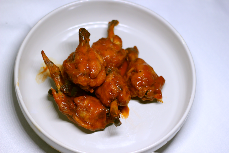 chicken wings covered in orange sauce sit on a white plate