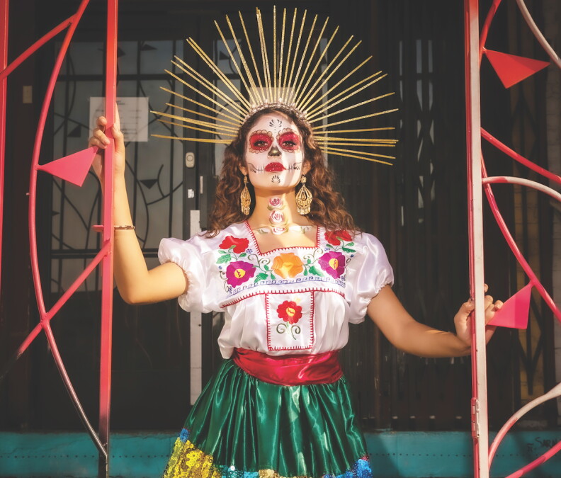 A performer from Ballet Folklorico de Los Angeles in traditional colorful clothing, face makeup and a headdress.