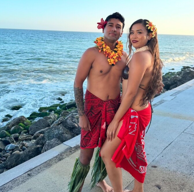 Man and women by the beach shore in traditional Aloha attire.