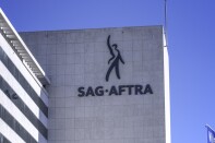A multi-story stone facade building has SAG- AFTRA on its side with a figure gesturing to the sky