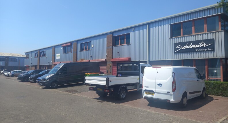 The exterior of a two-story office building with cars parked in front of it.