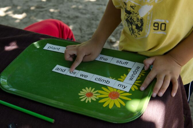 A preschool aged boy uses his recess time to play with a word puzzle.