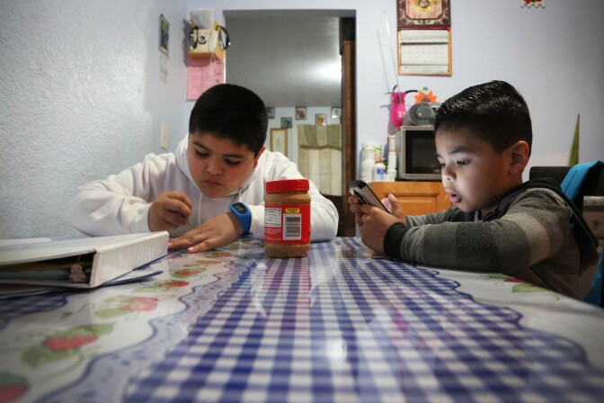 (Lt. to Rt.) Edwin Bernal, 9, finished homework, while his brother Angel Lozano, 5, watches videos before school at their home in Los Angeles, Friday January 20, 2017. Last year Edwin was among a group of undocumented children, who qualified for Medi-Cal coverage through a state funded program. His brother is covered because he was born in the United States. His mother fears that under the Trump administration the program will be in danger and he will no longer have medical coverage. (Photo By Maria J. Avila/CalMatters)