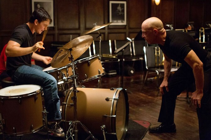 A still of actor Miles Teller and JK Simmons in the film Whiplash. Teller is on drums while Simmons is hunched over.
