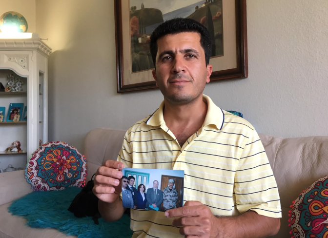 Kewa Sharif holds a photo of colleagues during the Iraq war, including his supervisor and his friend Rebaz. Both worked IT jobs supporting the U.S. military.