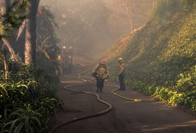 Firefighters work to save burning houses along Linda Flora Drive during the Skirball Fire in Los Angeles, California, December 6, 2017. The Skirball Fiire ignited before 5 a.m. on Wednesday and quickly engulfed 50 acres.