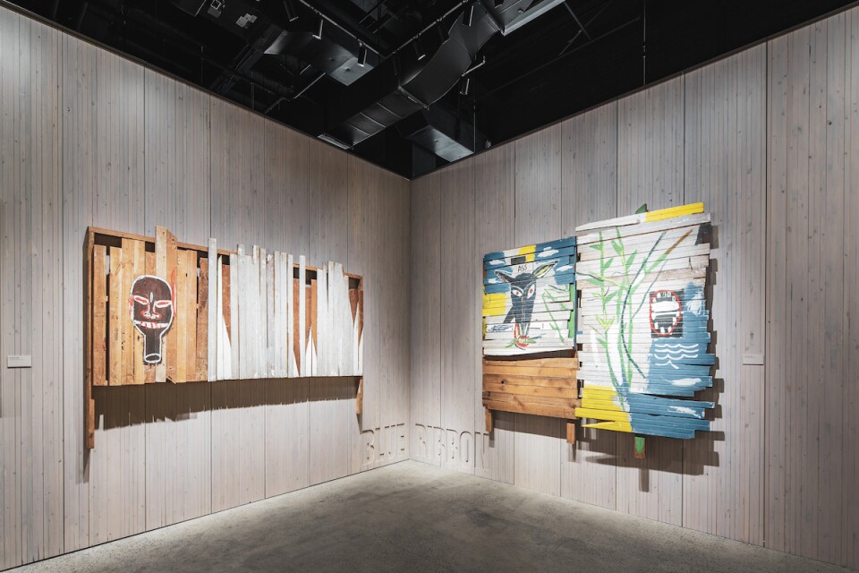 An image of two Basquiat works of painting on wood in a corner.