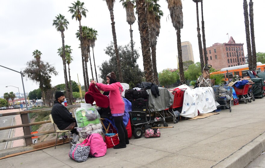 A woman folds clothes at a homeless encampment above a downtown Los Angeles freeway on May 12, 2015. A report released by the Los Angeles Homeless Authority on May 11 showed a 12% increase in the homeless population in both Los Angeles city and county, which according to the report have been driven by soaring rents, low wages and stubbornly high unemployment. One of the most striking findings from the biennial figures released saw the number of makeshift encampments, tents and vehicles occupied by the homeless increased 85%.  AFP PHOTO / FREDERIC J. BROWN        (Photo credit should read FREDERIC J. BROWN/AFP/Getty Images)