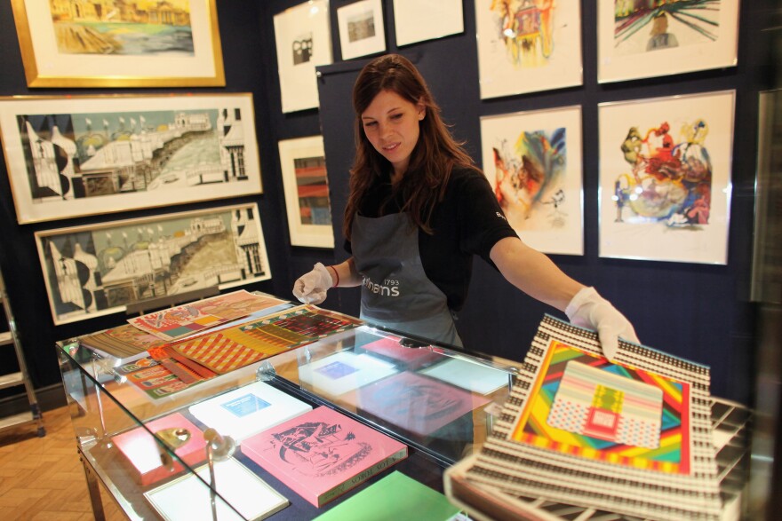 A gallery assistant adjusts a print in a set of 100 by Sir Eduardo Paolozzi estimated to fetch3,000 GBP in Bonhams auction house on November 25, 2011 in London, England. The auction of prints of works ranging from old masters to contemporary artists takes place in London on November 29, 2011.   