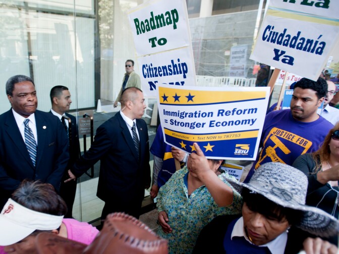 Security guards at 11111 Santa Monica Boulevard stand outside the entrance as marchers pass by. Hundreds of immigration reform supporters took part in a march on Wednesday to Senator Diane Feinstein's LA office. The march coincides with a immigration reform rally in Washington D.C.