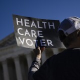 WASHINGTON, DC - NOVEMBER 10: A supporter of the Affordable Care Act (ACA) stands in front of the Supreme Court of the United States as the Court begins hearing arguments from California v. Texas about the legality of the ACA on November 10, 2020 in Washington, DC. Today is the first time that the Court is hearing a case with all three of President Donald Trump's appointments; Associate Justices Neil Gorsuch, Bret Kavanaugh, and Amy Coney Barrett. California v. Texas is the Republican's latest effort to dismantle the Affordable Care Act after repeated efforts to repeal the Act through the legislative process. (Photo by Samuel Corum/Getty Images)