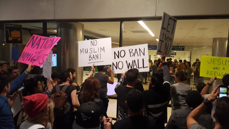 Protesters hold signs outside Terminal 2 at Los Angeles International Airport on Sunday, Jan. 29, 2017, amid calls to release immigrants detained under President Donald Trump's executive order effectively banning travel from seven majority Muslim nations.