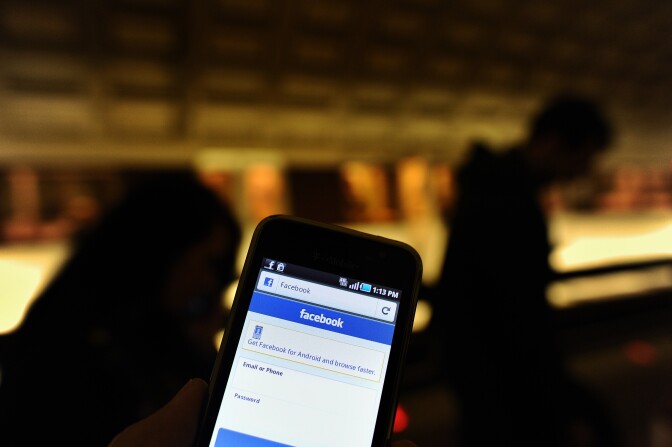 A man checks facebook on his smartphone while waiting for a train in a metro station in Washington, DC, on May 9, 2012. 
