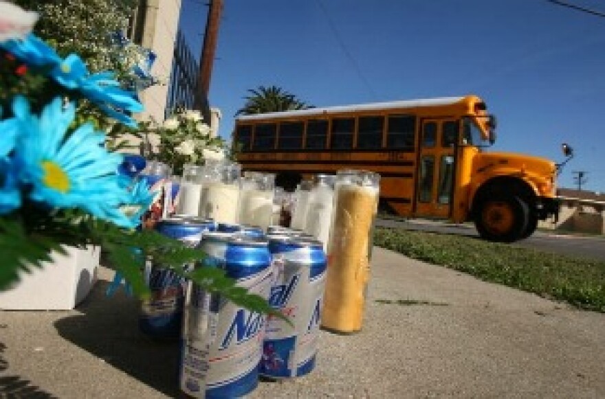 A school bus passes a memorial of candles, flowers, and other sundries to a slain suspected gang member who was killed there on January 31, 2009.
