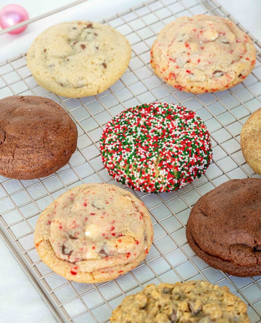A colorful assortment of cookies on a wire rack. A sprinkle cookie is in the center.