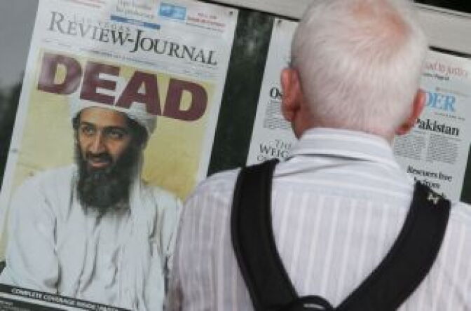 A passerby looks at newspaper headlines reporting the death of Osama Bin Laden, in front of the Newseum, on May 2, 2011 in Washington, DC.