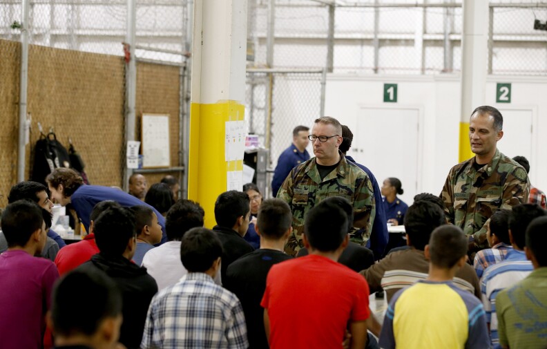 FILE - In Wednesday, this June 18, 2014, file photo, boys wait for medical appointments in a holding area where hundreds of mostly Central American immigrant children were being processed and held at the U.S. Customs and Border Protection Nogales Placement Center in Nogales, Ariz. The federal government has resumed checking the fingerprints of people other than parents who step forward to care for migrant children, like these shown, detained at the border amid concern by immigrant advocates that skipping the screening could put children at risk. (AP Photo/Ross D. Franklin, Pool)