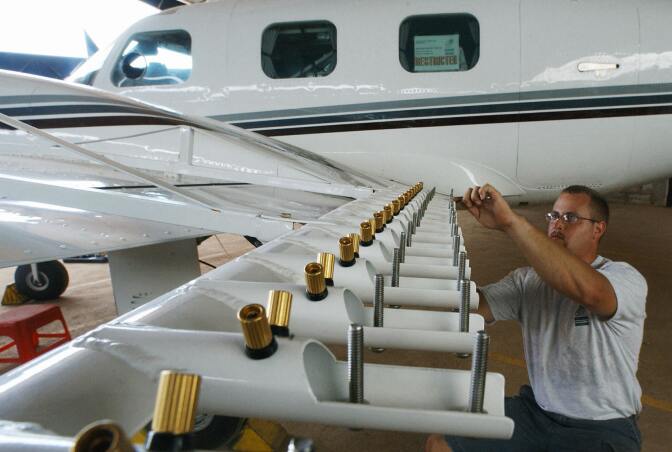 Aircraft technician Steve Bauer of US company Weather Modification Inc., inspects wing mounted burn-in silver iodide (dry ice) flare racks on a Piper Cheyenne II aircraft before the beginning of cloud-seeding operations.