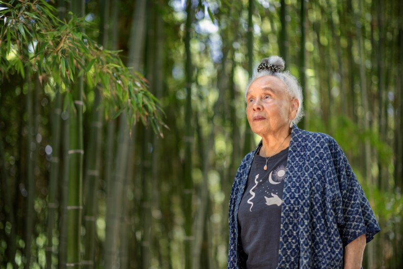 Artist Betye Saar, wearing a blue top, explores a bamboo grove in the Japanese Garden at The Huntington.