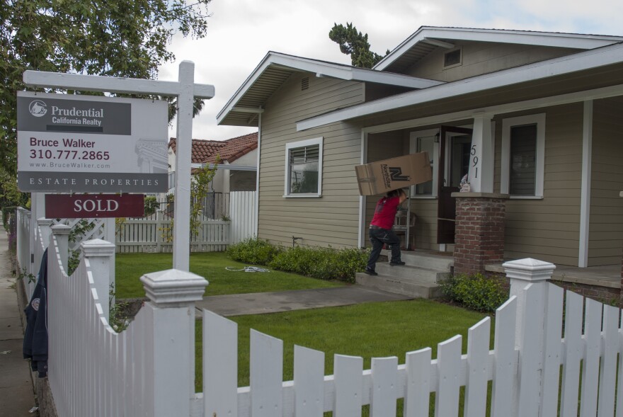 A mover from NorthStar Moving Corporation carries a cardboard box into a newly sold home in Central Los Angeles.