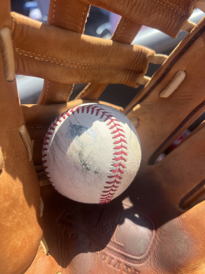 A close-up of a Dodgers practice ball, cupped in a leather glove.