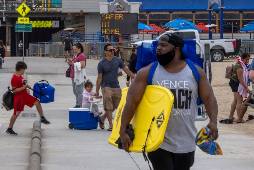 People walk near the Santa Monica Pier as crowds gather on Memorial Day as shutdowns are relaxed more than a year after Covid-19 pandemic shutdowns began, in Santa Monica, California on May 31, 2021. (Photo by DAVID MCNEW / AFP) (Photo by DAVID MCNEW/AFP via Getty Images)