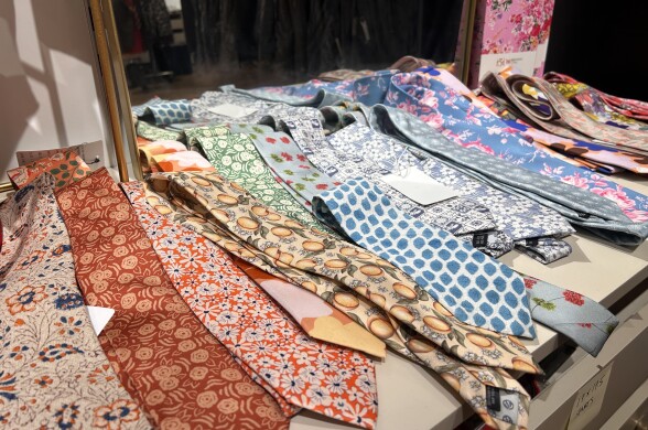 At least a dozen colorful ties are laid out on top of a dresser with a mirror attached to the top.