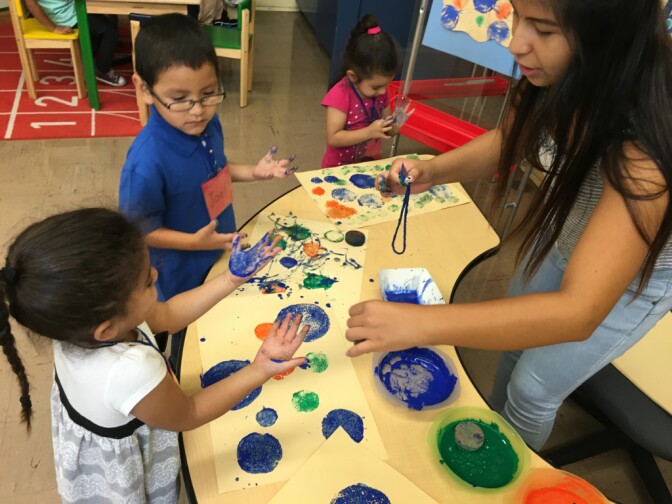 Glassell Park ETK teacher, Ms Pineda, works with a small group of six children on a sponge painting project. 