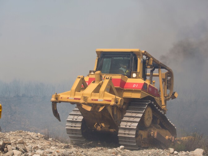 San Bernardino County Fire brings in a bulldozer to fight flames north of Banyan Street as the Etiwanda Fire burns in Rancho Cucamonga on Wednesday, April 30, 2014.