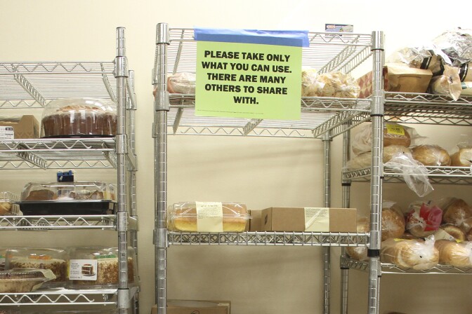 Three metal racks with various food items. On the middle rack there's a yellow piece of paper taped onto it that reads, "Please take only what you can use. There are many others to share with."
