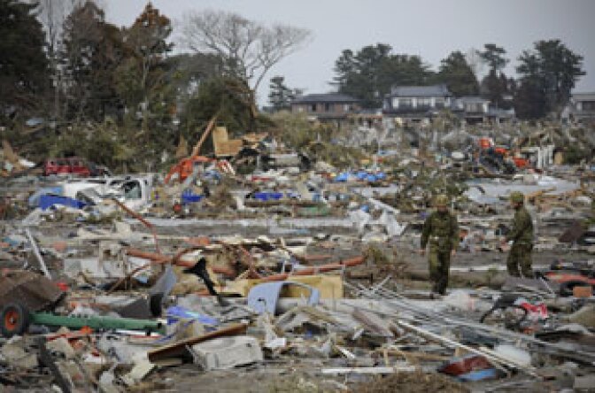 Japanese self defense personnel walk amongst a tsunami devastated town, close to the airport in Sendai on March 14, 2011.