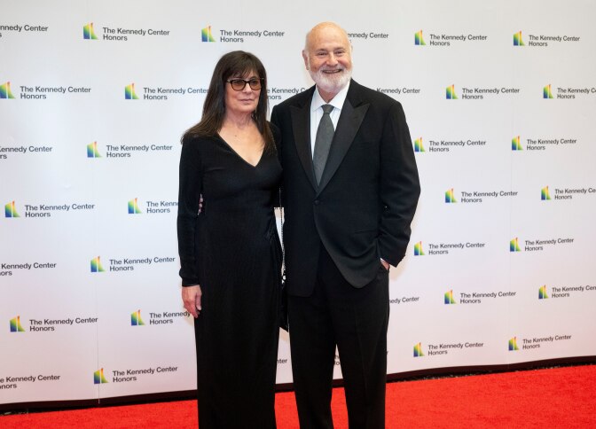 A man and woman in formal close pose on a red carpet.