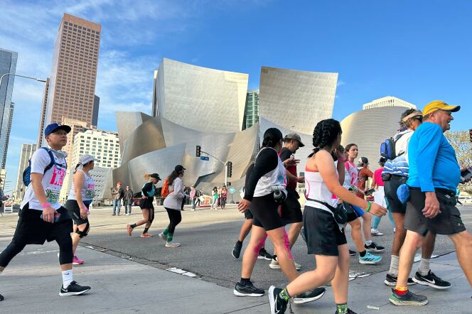 Runners and walkers running past a silver building in odd shape