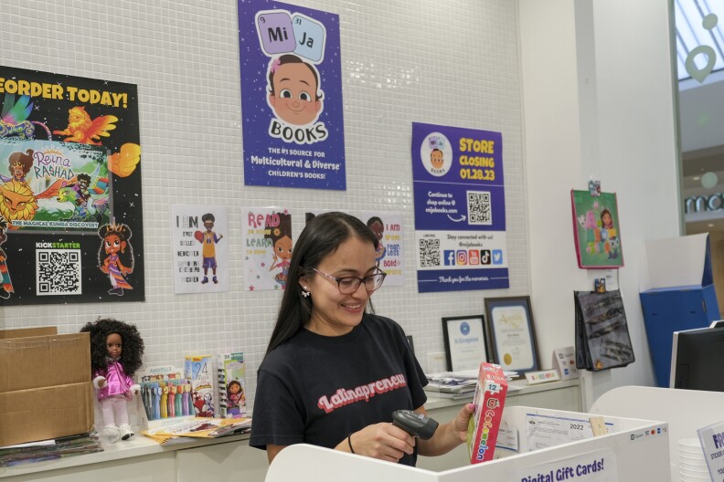 A medium skin tone woman scans the barcode on a puzzle at a children's bookstore.