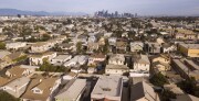 Aerial view of housing in Los Angeles with a view to the city's downtown skyline in the distance.