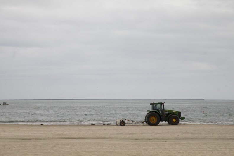 A tractor rakes up the debris on the beach, Thursday, June 4, 2015, in Long Beach, Calif.  A 4-mile stretch of a Los Angeles-area beach was closed Thursday to swimmers and surfers after tar balls washed ashore — the latest Southern California coastline to shut down due to oily goo, authorities said. 
