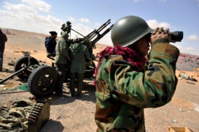 A Libyan rebel fighter scans the horizon at the entrance to the oil-rich town of Ras Lanuf.