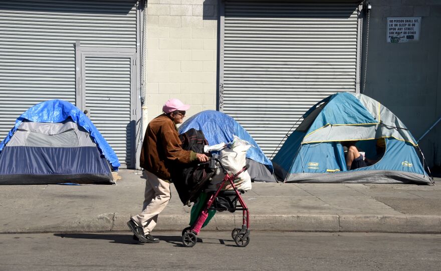 A woman pushes her walker past tents housing the homeless in Los Angeles, California on February 9, 2016.