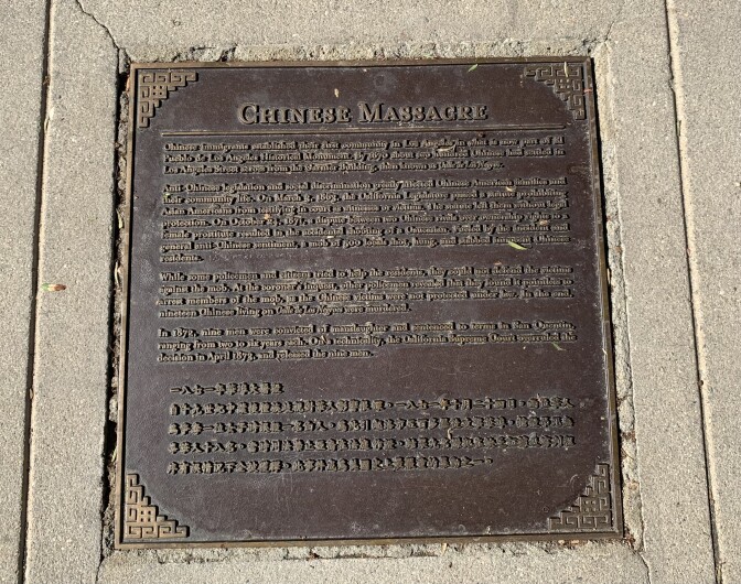 A close-up of a bronze sidewalk plaque with both English and Chinese font.