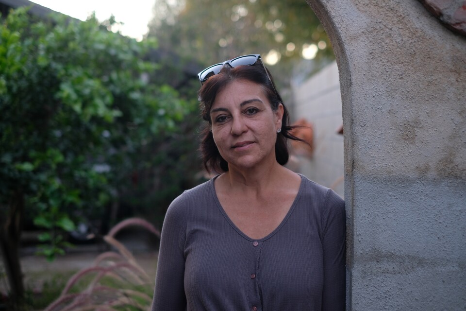 A woman with medium skin tone and dark hair stands in an outdoor archway.