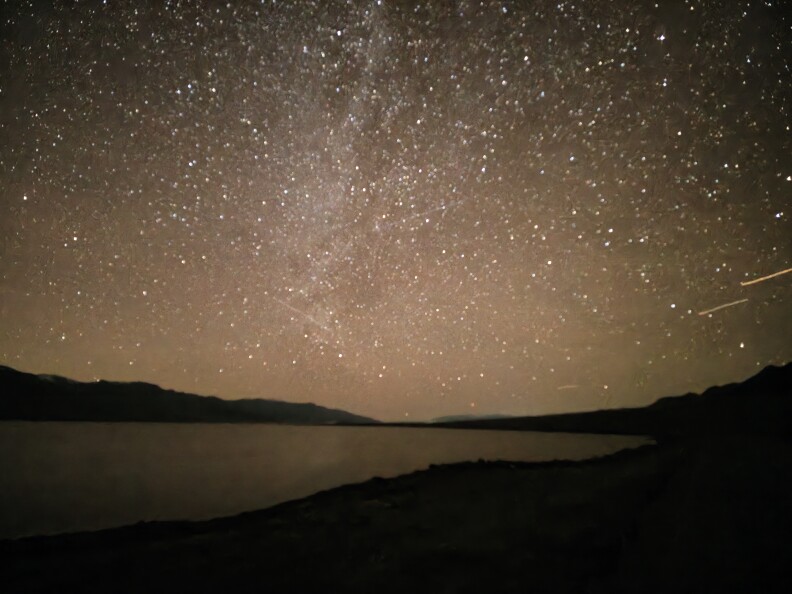 Night sky filled with stars above a quiet lake.