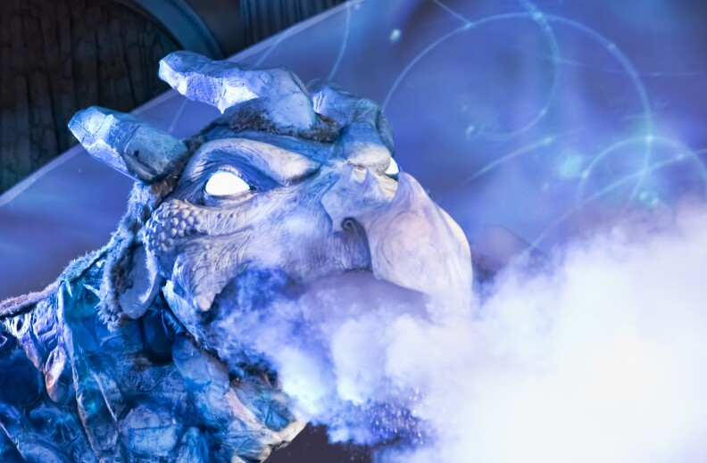 A large dragon head puppet, with "cryo" smoke shooting out of its mouth. The dragon is blue and white, with solid white glowing eyes, against a blue background.