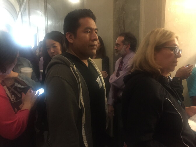 Restaurant worker Juan Moran waits near the front a long line to enter City Council Chambers