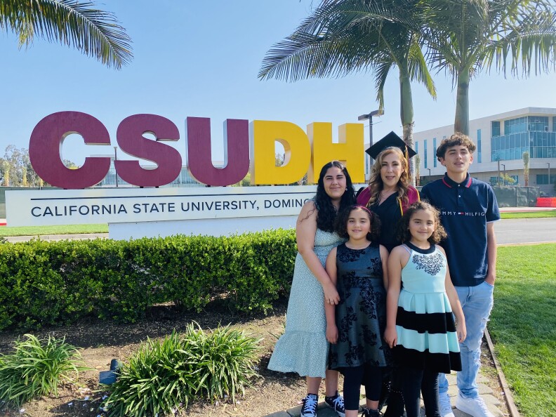 California State University Dominguez Hills graduating student Elizabeth Valdivia with her four kids in front of campus sign.