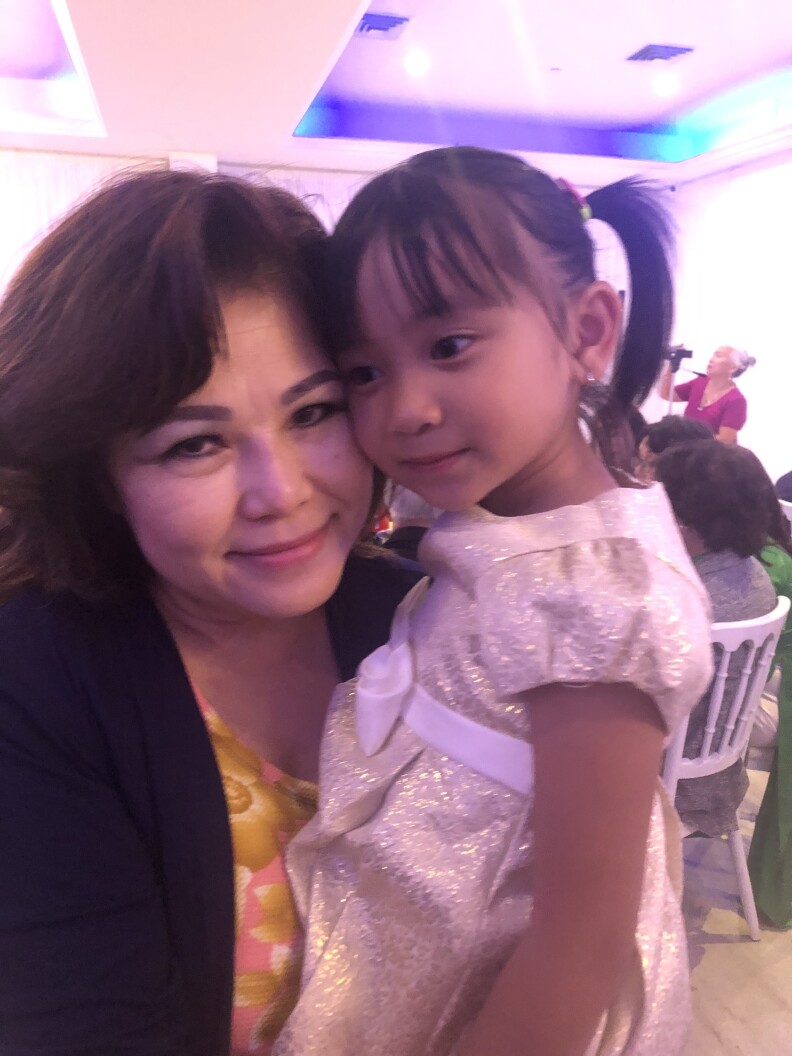 A Vietnamese American woman and a girl in formal outfits pose for the camera. 